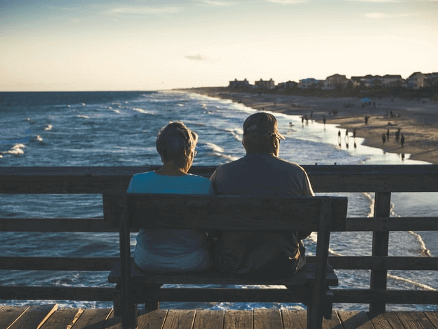 old couple sitting on a bench near the seaside