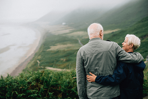 an old couple looking at each other in front of a scenery